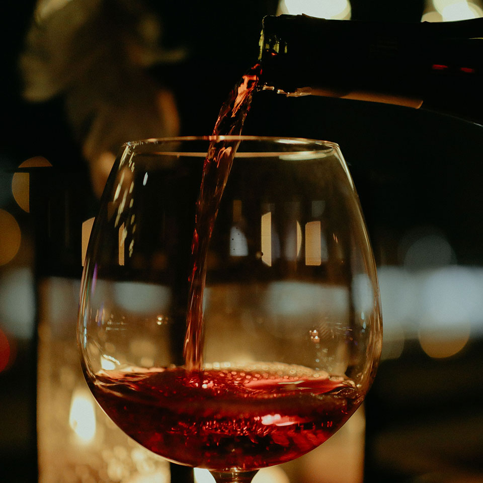 Red wine pouring into a glass for an exclusive French wine dinner menu